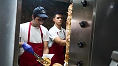 Kucharz grillowy Thomas Siamandas przygotowuje tradycyjne souvlaki w restauracji w centralnej dzielnicy Monastiraki podczas upalnego dnia w Atenach w środę, 16 lipca 2025 r.