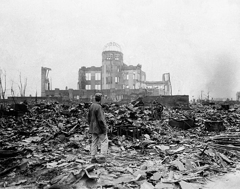 An allied correspondent stands in a sea of rubble before the shell of a building that once was a movie theatre in Hiroshima, 8 September, 1945