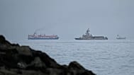 A UAE navy ship sails next to a cargo ship in the Strait of Hormuz as seen from Khor Fakkan, 11 March, 2026