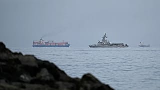 A UAE navy ship sails next to a cargo ship in the Strait of Hormuz as seen from Khor Fakkan, 11 March, 2026