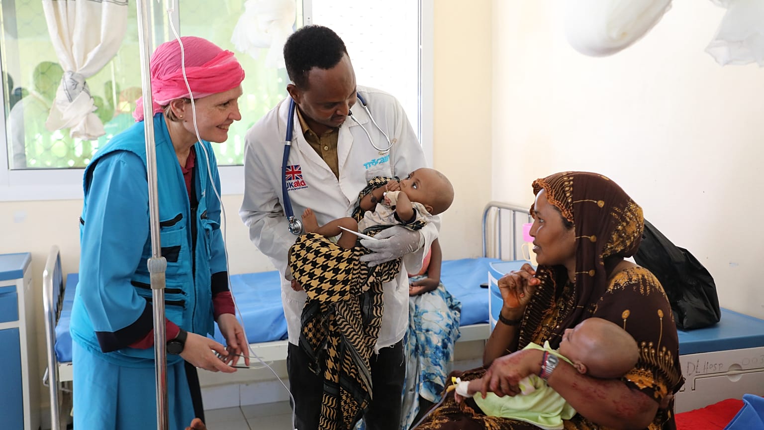 Un representante de UNICEF en Somalia sonríe a una madre de dos niños desnutridos en el Hospital de Referencia de Dolow, en el sur de Somalia.