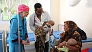 Un representante de UNICEF en Somalia sonríe a una madre de dos niños desnutridos en el Hospital de Referencia de Dolow, en el sur de Somalia.
