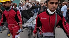 Mitglieder des Iranischen Roten Halbmonds und Helfer tragen einen schwarzen Sack mit der Leiche eines Opfers nach einem US-Israel-Angriff auf ein Wohnhaus.