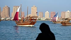 امراة تلتقط صور لقوارب شراعية بألوان علم الولايات المتحدة وقطر 