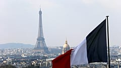 يظهر العلم الفرنسي فوق أفق العاصمة الفرنسية مع برج إيفل وقبة المعاقين وأسطح المنازل من رواق قبة البانثيون في باريس. 