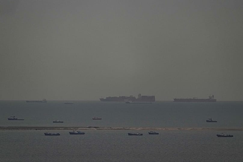 Fishing boats dot the sea as cargo ships sail through the Arabian Gulf toward the Strait of Hormuz off the United Arab Emirates, 27 March, 2026