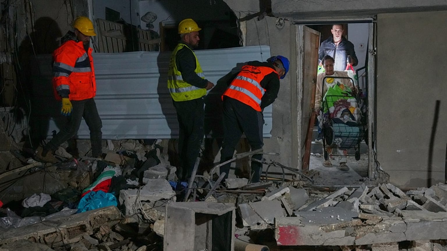 Residents carry personal belongings as they leave a building damaged in a missile strike in Tel Aviv, Israel, early Saturday, March 28, 2026