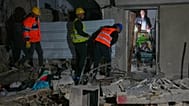 Residents carry personal belongings as they leave a building damaged in a missile strike in Tel Aviv, Israel, early Saturday, March 28, 2026