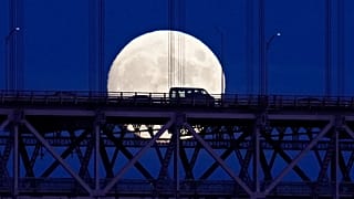 Os veículos que atravessam a ponte 25 de Abril recortam-se contra a lua nascente à medida que a noite cai em Lisboa, na sexta-feira, 9 de setembro de 2022.