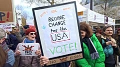 Demonstrierende mit Anti-Trump-Plakaten auf einer Kundgebung.
