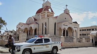 عنصر في قوى الأمن الداخلي السوري يجلس على سيارة متوقفة خارج كنيسة في بلدة السقيلبية ذات الأغلبية المسيحية، غرب حماة، سوريا، السبت 28 مارس 2026، 