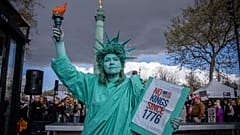 Eine als Freiheitsstatue verkleidete Frau nimmt an der "No Kings"-Demonstration in Paris, Frankreich, am Samstag, 28. März 2026, teil.