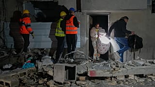 يحمل سكانٌ أمتعتهم الشخصية أثناء مغادرتهم مبنى تضرر جرّاء ضربة صاروخية في تل أبيب، إسرائيل، في وقت مبكر من صباح السبت 28 مارس/آذار 2026. (تصوير: مايا ليفين/أسوشيتد برس)