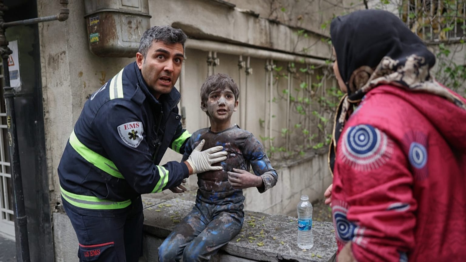 A first responder assists an injured boy following a strike that hit a residential building amid the U.S.-Israeli military campaign in Tehran, Iran, Saturday, March 28, 2026