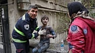 A first responder assists an injured boy following a strike that hit a residential building amid the U.S.-Israeli military campaign in Tehran, Iran, Saturday, March 28, 2026