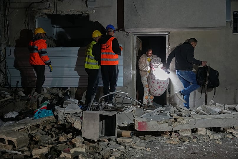 Residents carry personal belongings as they leave a building damaged in a missile strike in Tel Aviv, Israel, early Saturday, March 28, 2026