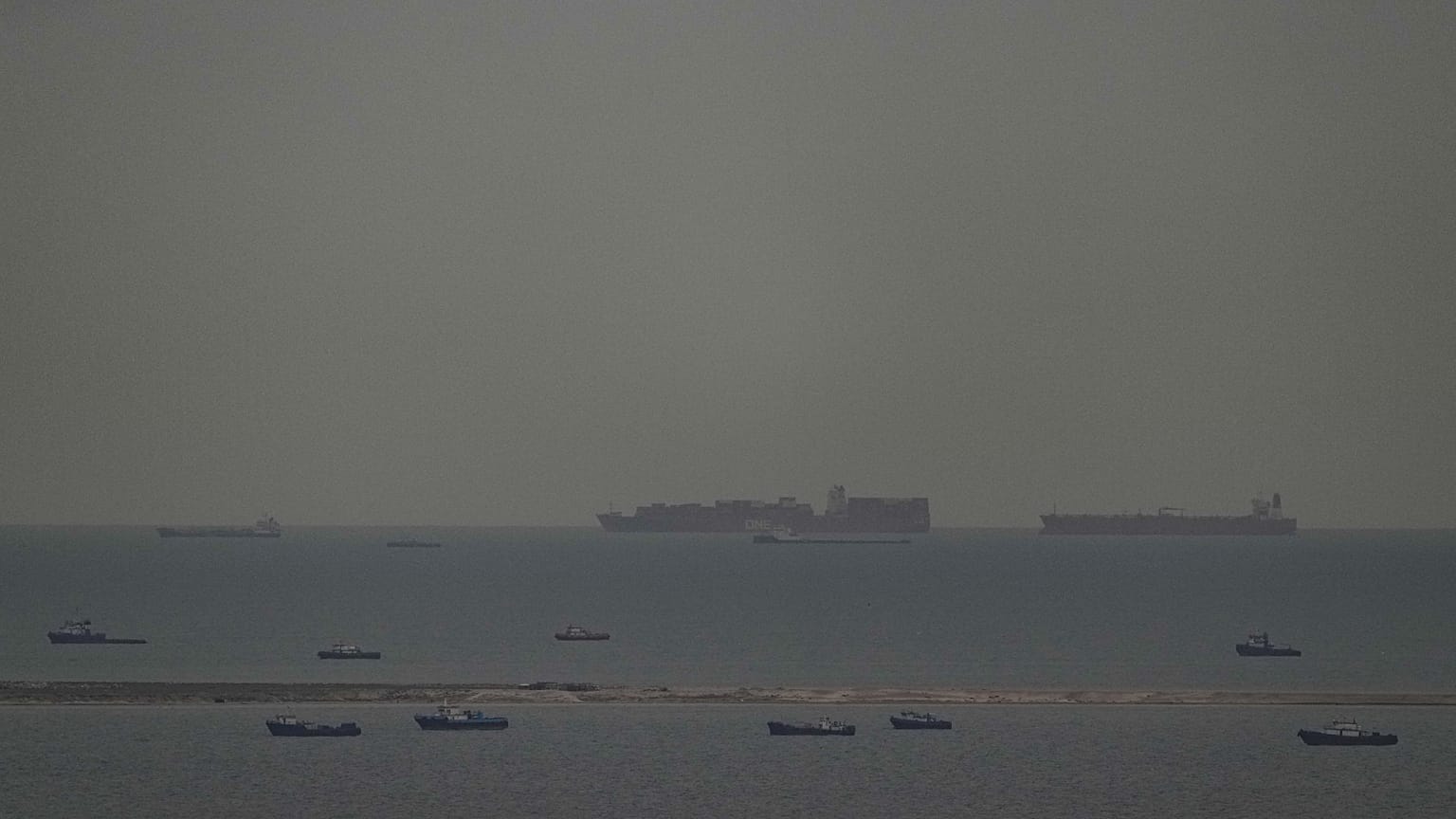 Fishing boats dot the sea as cargo ships, in the background, sail through the Arabian Gulf toward the Strait of Hormuz off the United Arab Emirates, Friday, March 27, 2026. 