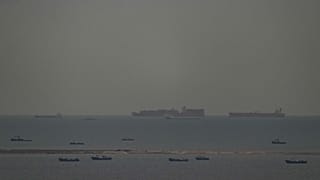 Fishing boats dot the sea as cargo ships, in the background, sail through the Arabian Gulf toward the Strait of Hormuz off the United Arab Emirates, Friday, March 27, 2026. 
