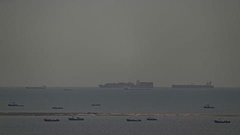 Fishing boats dot the sea as cargo ships, in the background, sail through the Arabian Gulf toward the Strait of Hormuz off the United Arab Emirates, Friday, March 27, 2026. 
