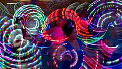 Hoopers treten am Freitag, den 27. Juli 2012, mit beleuchteten Hula-Hoops bei einem Flashmob am Potsdamer Platz in Berlin auf.
