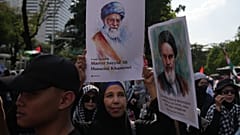 Una mujer muestra una foto del difunto líder supremo de Irán, el ayatolá Ali Jamenei.