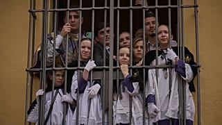 Monaguillos se agolpan junto a una ventana para presenciar el paso del Cristo de la hermandad de San Bernardo durante la Semana Santa en Sevilla, el 16 de abril de 2025.
