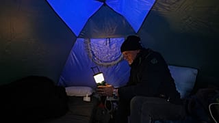 رجل يحمل مصباحًا داخل خيمة في مأوى مؤقت لنازحين من الغارات الإسرائيلية في الضاحية الجنوبية لبيروت، يوم الأحد 22 مارس 2026.