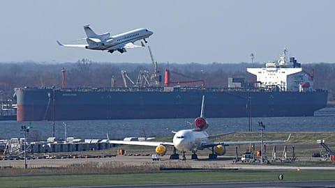 An airplane takes off in view of a crude oil tanker from the Philadelphia International Airport, 26 March 2026