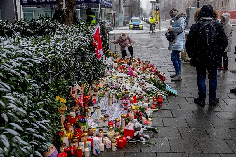 Flowers and candles were laid near the spot where a car drove into a group of protesters in February 2025 three days after the attack,