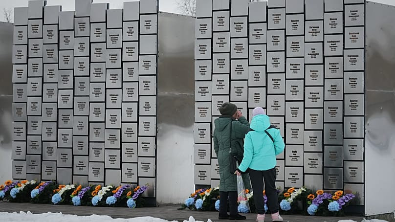 Relatives of those killed during the Russian occupation stand near the Wall of Remembrance in Bucha, Ukraine, Tuesday, Feb. 24, 2026