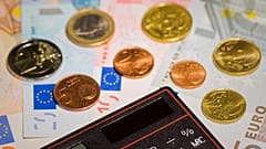 Stockfotografie von Geld, einem Taschenrechner und einem Spielzeughaus.