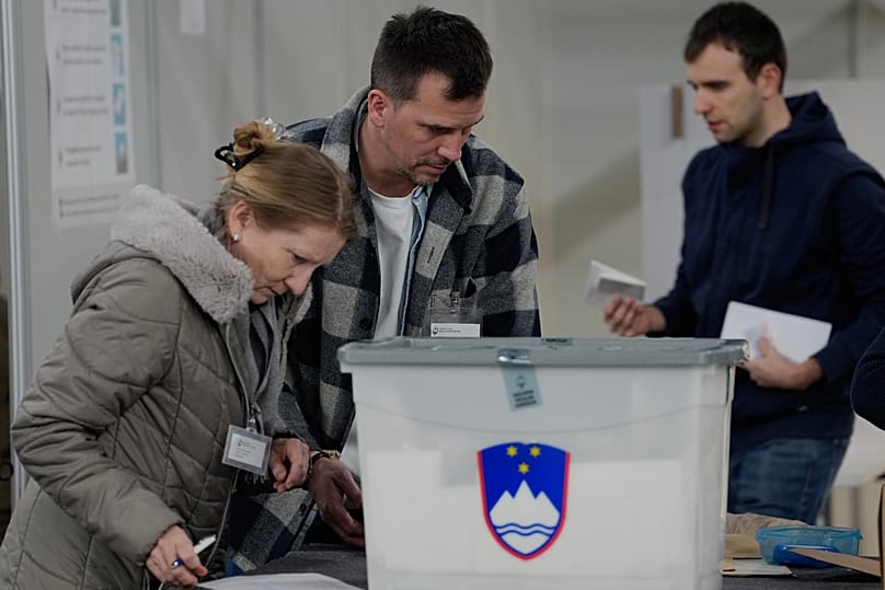 Members of the electoral commission handle ballots at a sports hall turned polling station for early voting in Ljubljana, 18 March, 2026