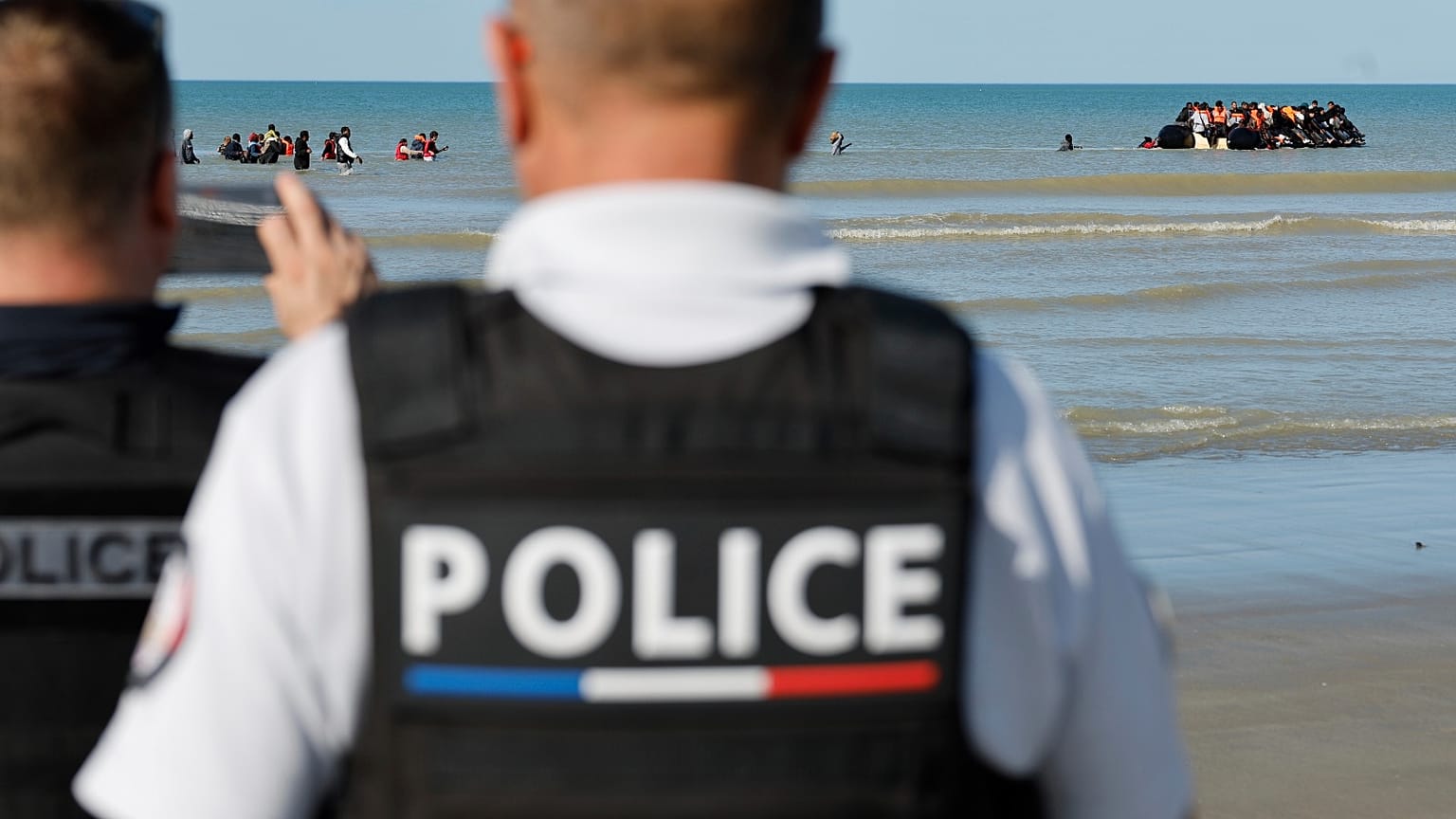 ضباط الشرطة الفرنسية يلتقطون صوراً للمهاجرين أثناء صعودهم على متن قارب صغير للوصول إلى بريطانيا، في جرافلين، شمال فرنسا، فرنسا، الجمعة 19 سبتمبر 2025. 