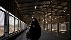تعبر امرأة تحمل متعلّقاتها معبر شلمجة الحدودي بين إيران والعراق، قرب مدينة البصرة في العراق، الأحد 29 مارس/آذار 2026. 