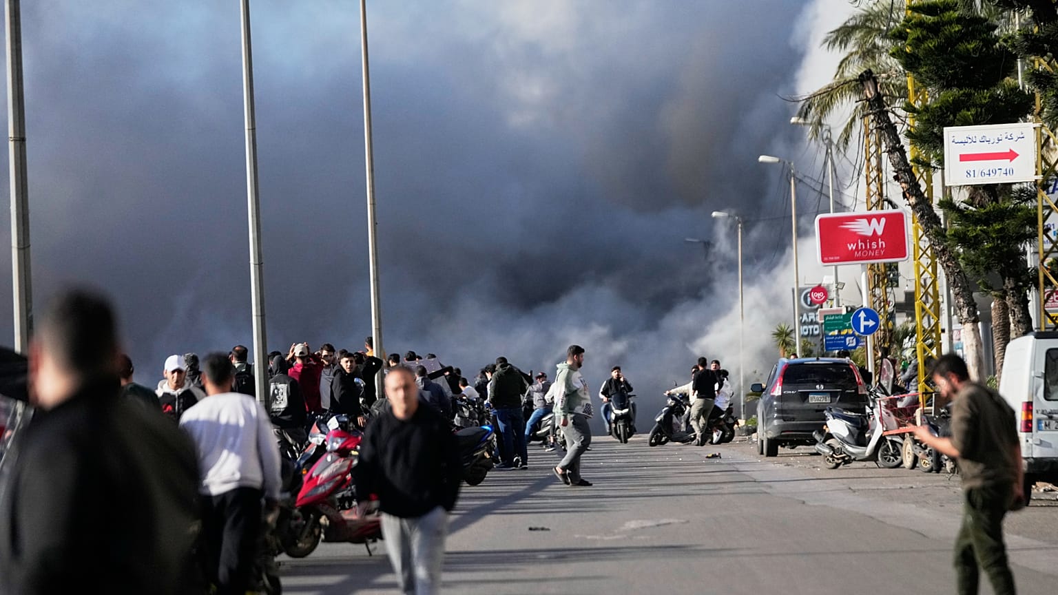El humo se eleva mientras viandantes observan tras un ataque israelí contra un edificio junto a la carretera al aeropuerto de Beirut el 31 de marzo de 2026.