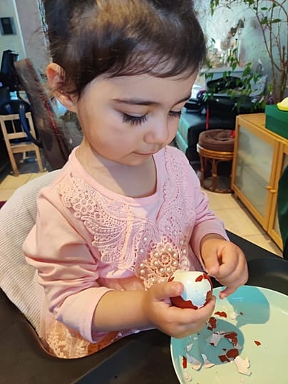 Ребёнок чистит пасхальное яйцо 