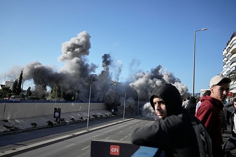 Des passants observent la fumée qui s'élève après une frappe israélienne près de la route menant à l'aéroport de Beyrouth, au Liban, mardi 31 mars 2026. 
