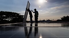 Zwei Solartechniker wuchten in Manila ein Solarpanel auf das Dach eines Wohnhauses, Philippinen, 30. April 2026.