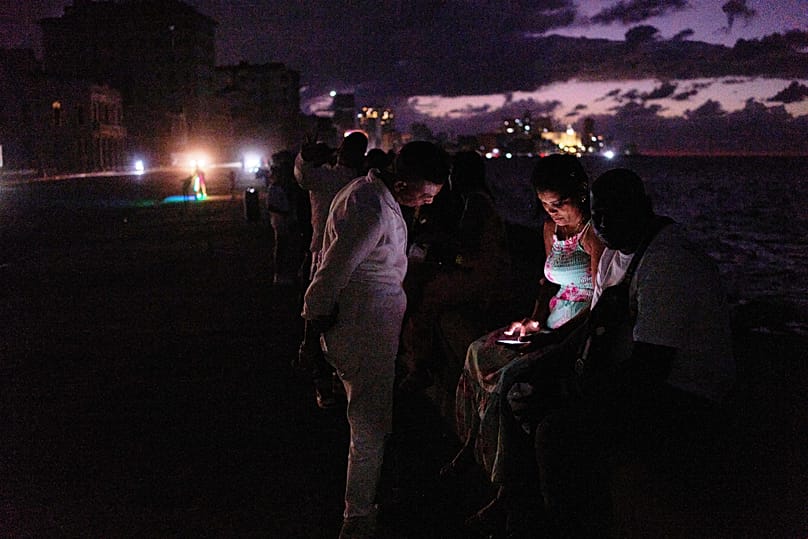 People spend the night in the dark on the Malecon during a blackout in Havana, 21 March, 2026