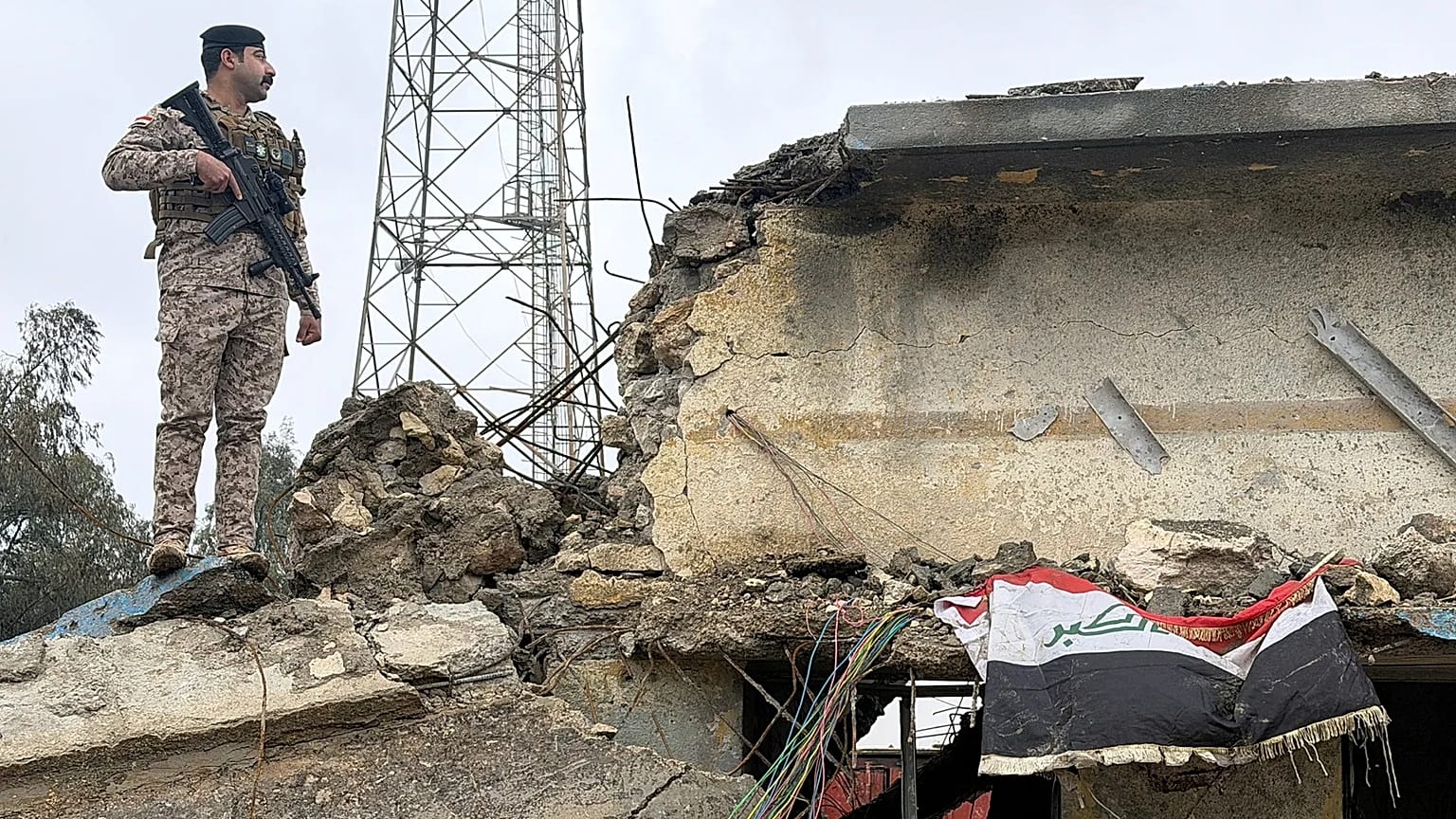 جندي عراقي يقف حارساً على سطح مبنى متضرر في قاعدة الجيش العراقي في الحبانية بعد تعرضه لغارة جوية
