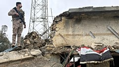 جندي عراقي يقف حارساً على سطح مبنى متضرر في قاعدة الجيش العراقي في الحبانية بعد تعرضه لغارة جوية