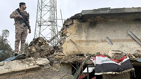 جندي عراقي يقف حارساً على سطح مبنى متضرر في قاعدة الجيش العراقي في الحبانية بعد تعرضه لغارة جوية