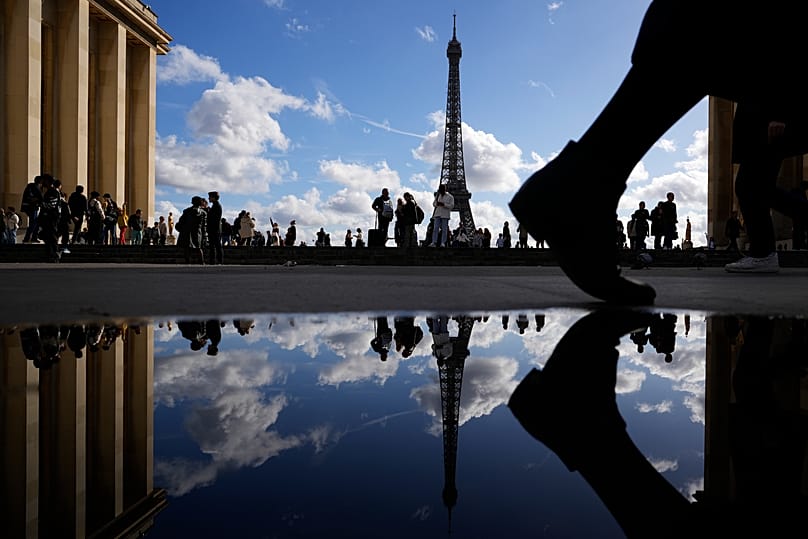 The Eiffel Tower reflected in a puddle as people walk past at the Trocadero square in Paris, 24 October, 2023
