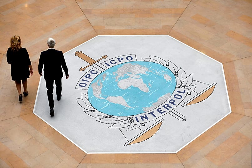 People walk on the Interpol logo at the international police agency headquarters in Lyon, 8 November, 2018