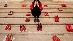 Eine junge Frau posiert zwischen roten Schuhen, die Solidarität mit Opfern häuslicher Gewalt zeigen, bei einer Aufklärungsveranstaltung in Bukarest, Rumänien, Ende März 2026.