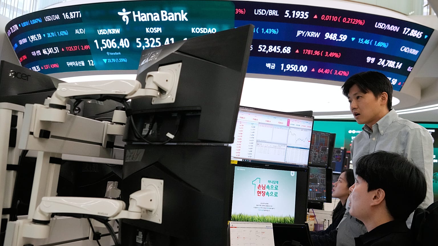 Güney Kore'de KOSPI endeksini gösteren ekranın önünde monitörleri izleyen döviz yatırımcıları, 1 Nisan 2026