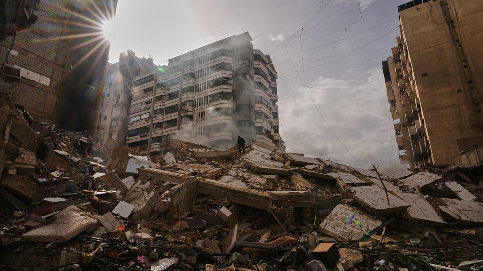يقف رجل فوق الأنقاض فيما يتصاعد الدخان من مبنى دُمّر جراء غارة جوية إسرائيلية في الضاحية، الضاحية الجنوبية لبيروت، لبنان، 14 آذار/مارس 2026