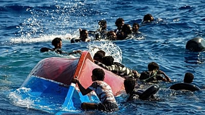 Migrantes en una barca de madera piden ayuda mientras son asistidos durante una operación de rescate al sur de la isla italiana de Lampedusa, 11 de agosto de 2022.