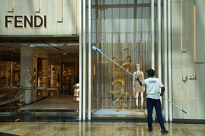 رجل ينظّف واجهة متجر داخل "مول الإمارات" في دبي، الخميس 17 أبريل 2025.