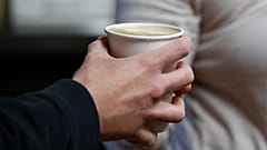 كارلي فالزر (الخلفية) تسلم العميل فنجانًا من القهوة في Blue Beagle Coffee 